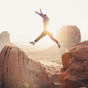 man jumping from one cliff to another