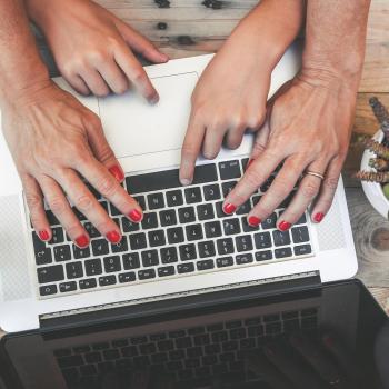 female hands and child hands typing on laptop keyboard